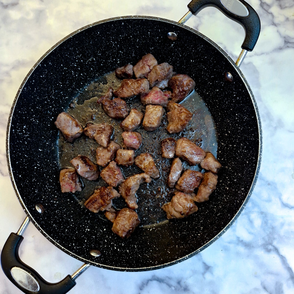 Pieces of seasoned browning in a frying pan.