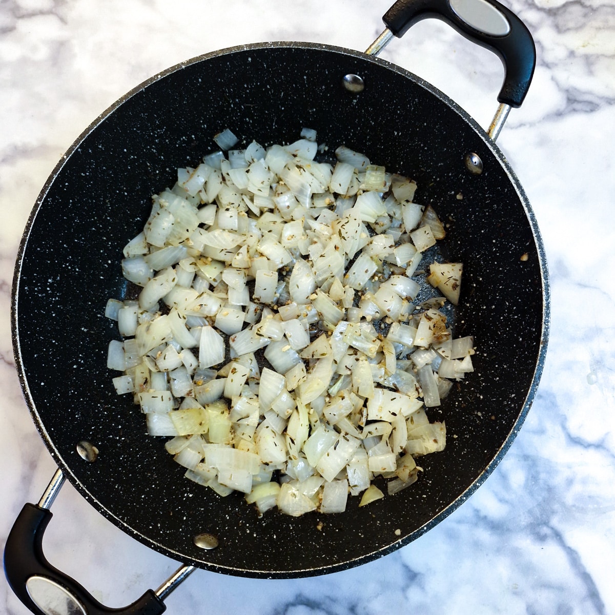 Chopped onions frying in a frying pan.