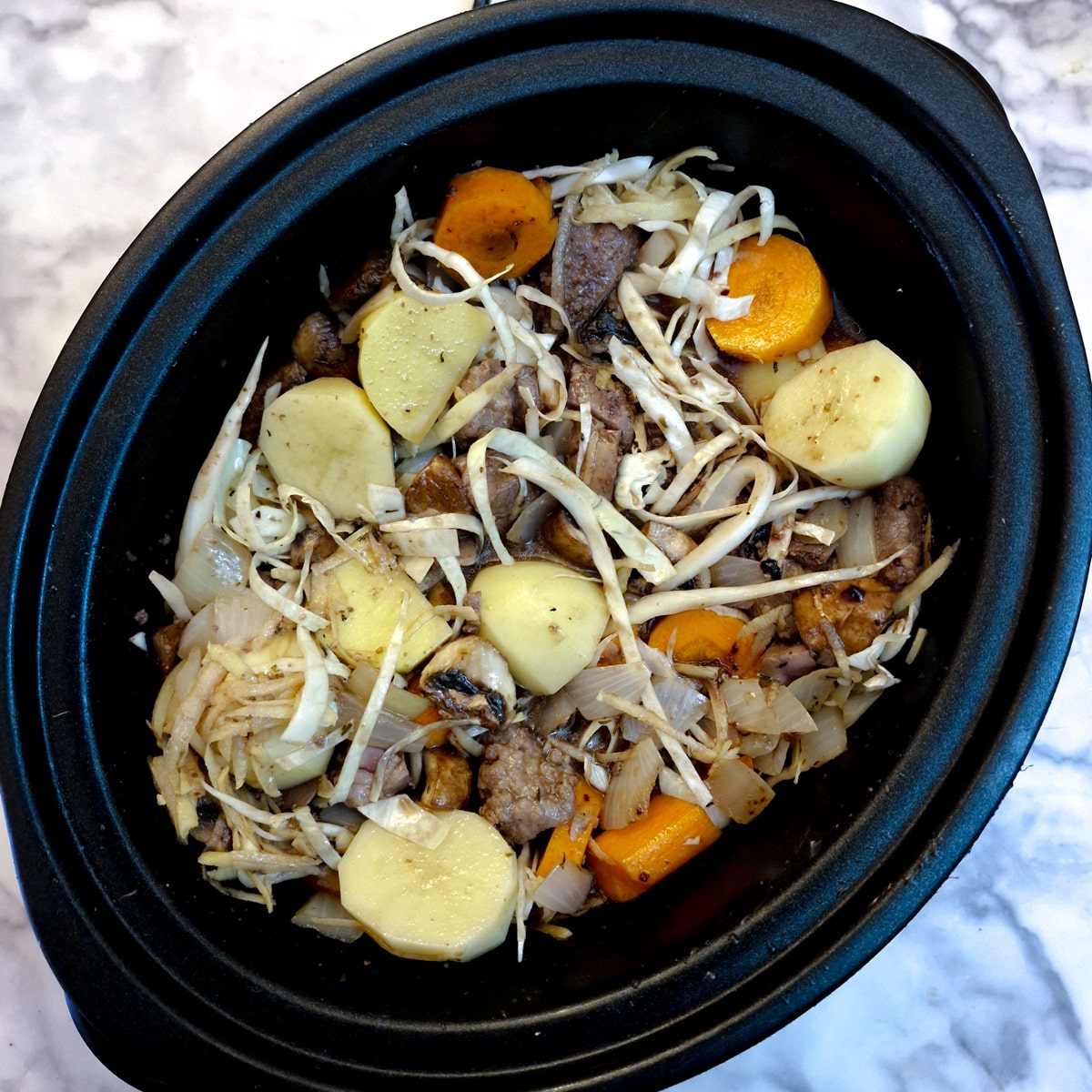 Potatoes, carrots and shredded cabbage added to the slow-cooker with stock.