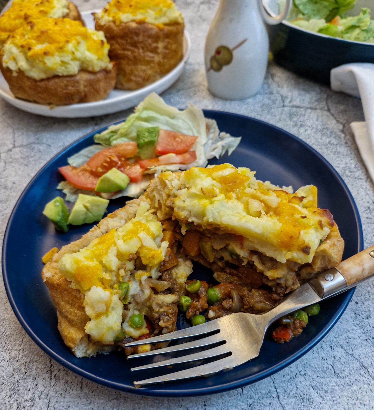 A stuffed Yorkshire pudding pie on a blue plate, cut open to show the inside.