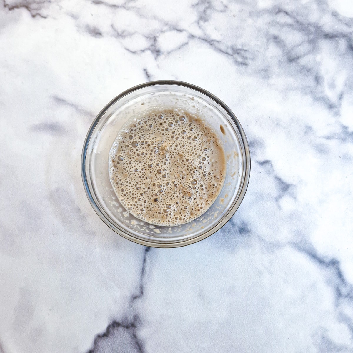 Yeast activating in a small glass bowl.