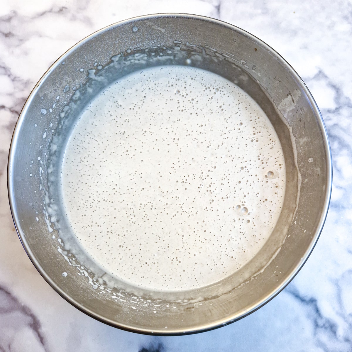 Crumpet batter that has stood for 30 minutes, showing the bubbles that have formed.