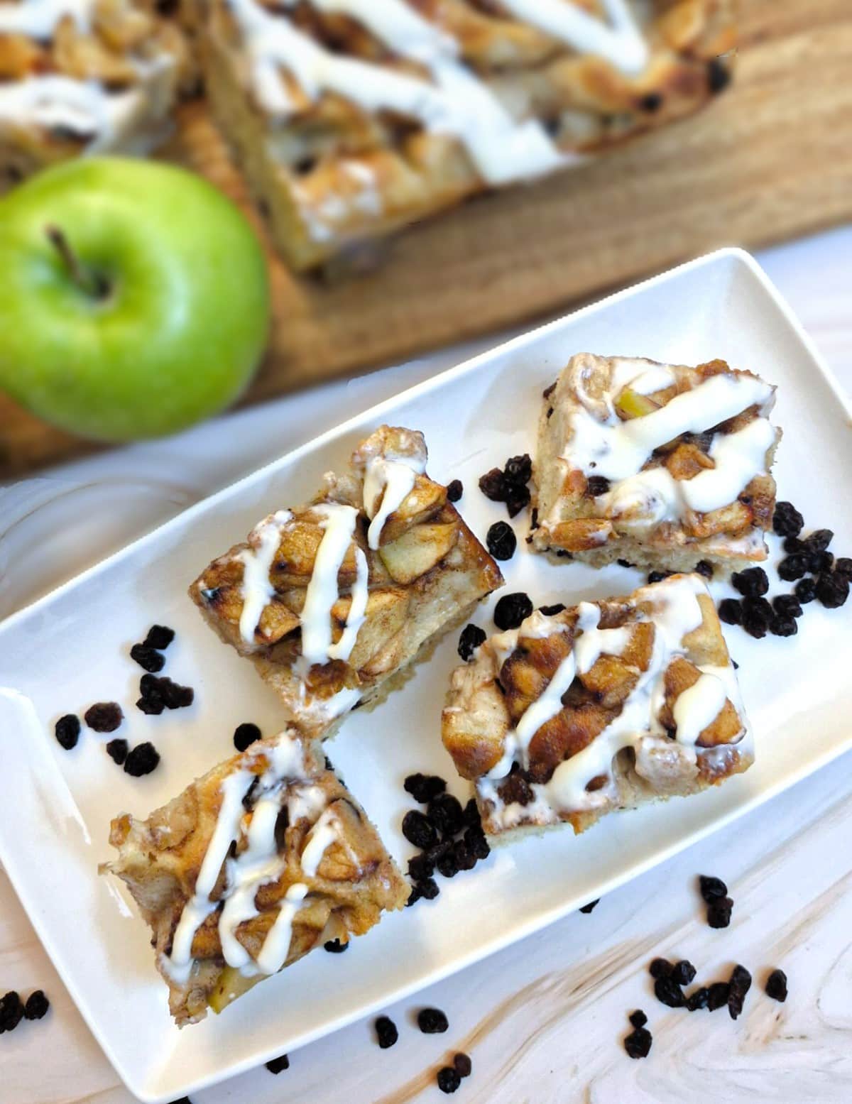 Overhead shot of 4 pieces of apple and raisin focaccia on a white plate.