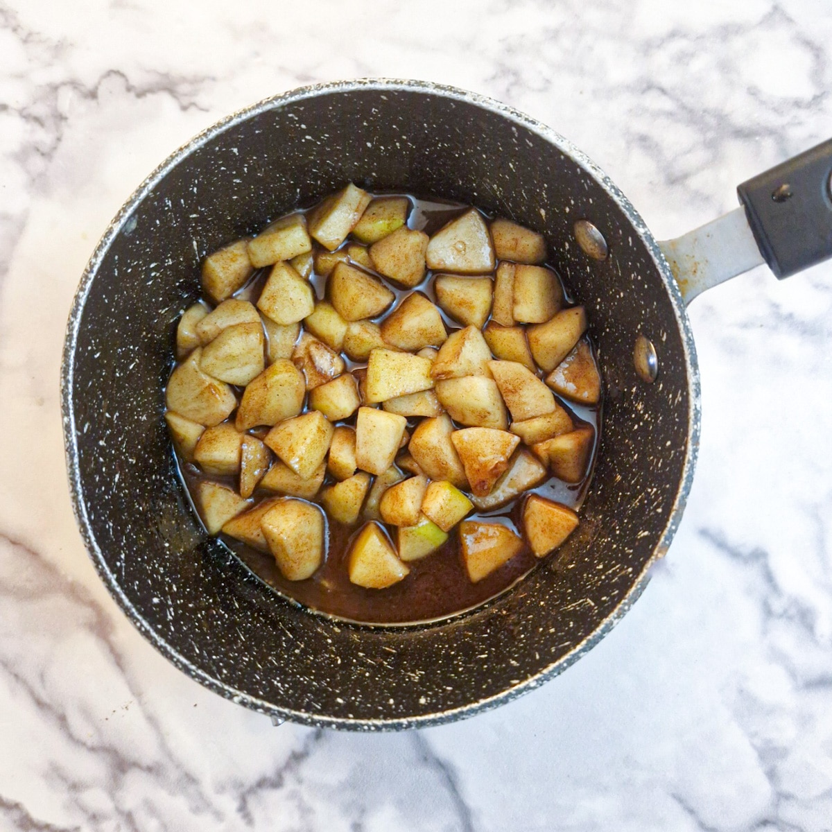 Pieces of apple that have been softened in butter and sugar in a small saucepan.