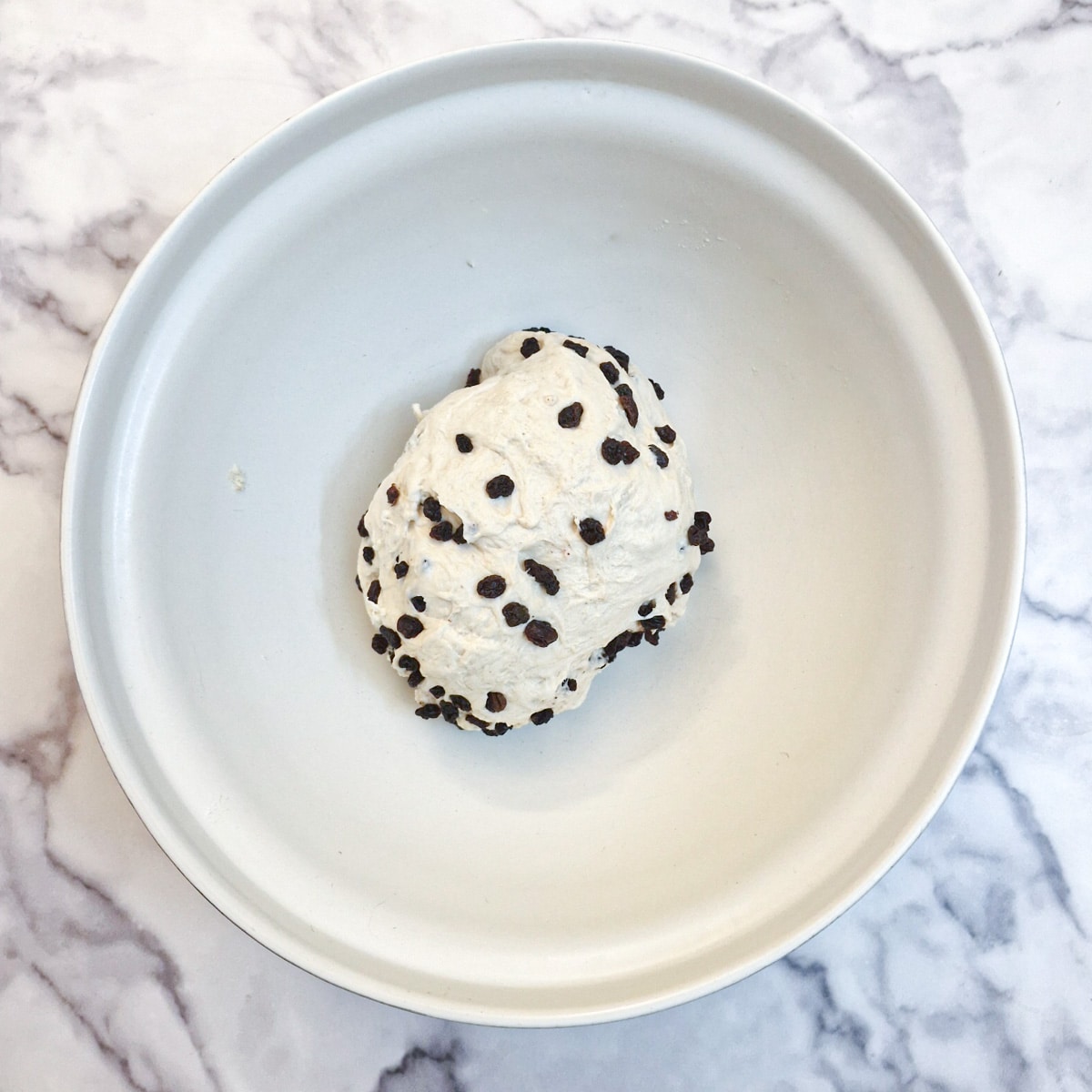 A ball of focaccia dough that has been mixed with raisins.