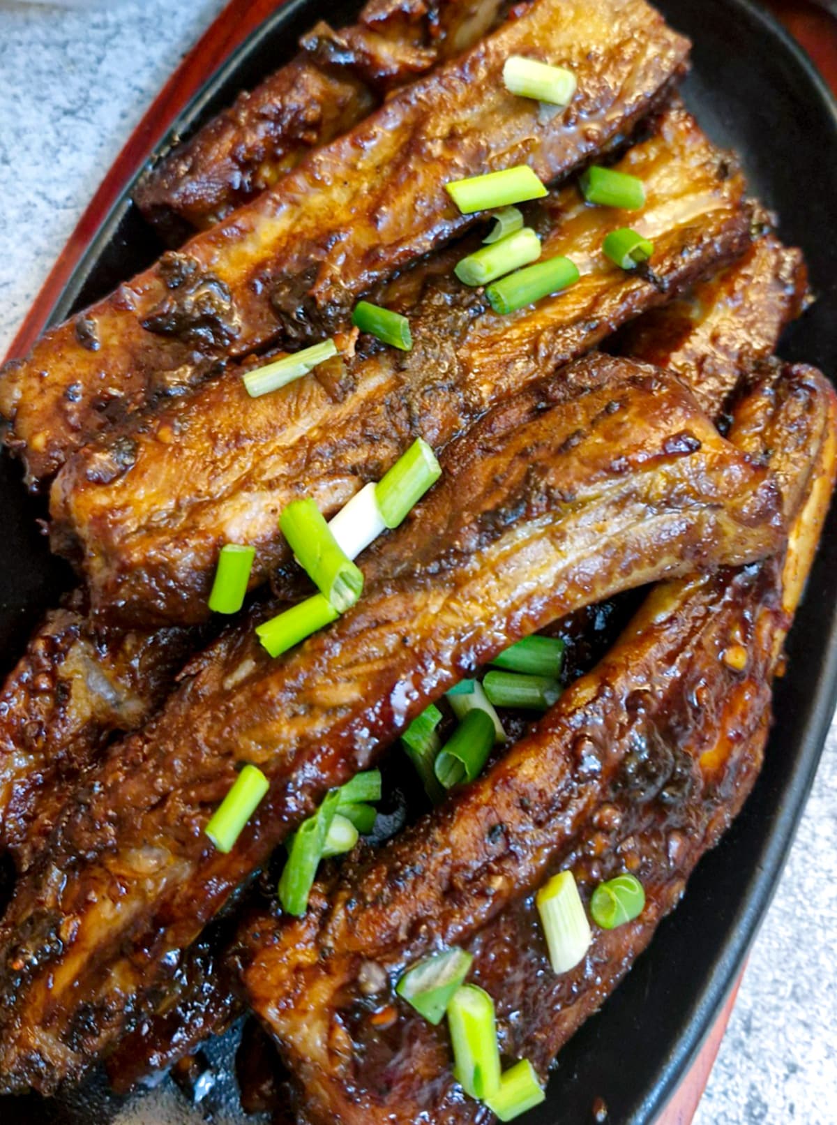 Close up of pork spareribs garnished with spring onions.