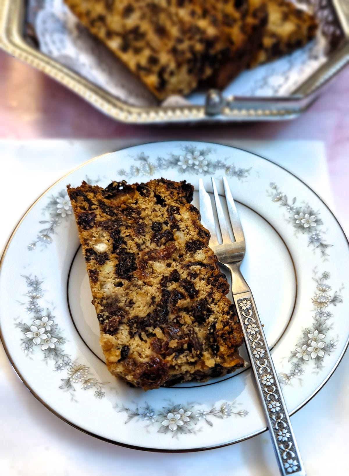 A slice of condensed milk fruit cake on a patterned plate.