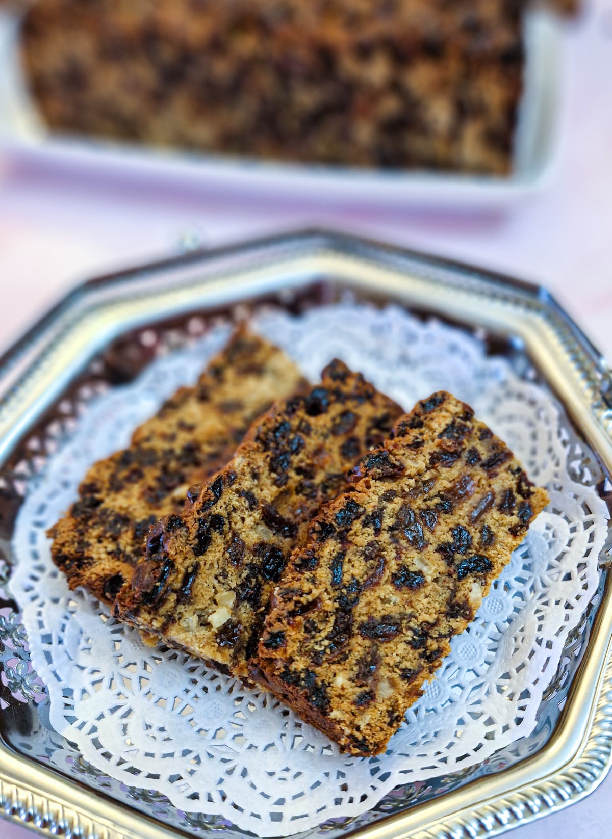 Three slices of Baileys fruit cake on a silver plate lined with a white doily.