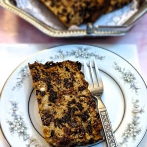 A slice of condensed milk fruit cake on a patterned plate.