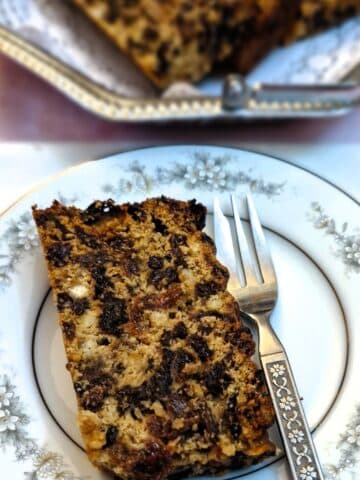 A slice of condensed milk fruit cake on a patterned plate.