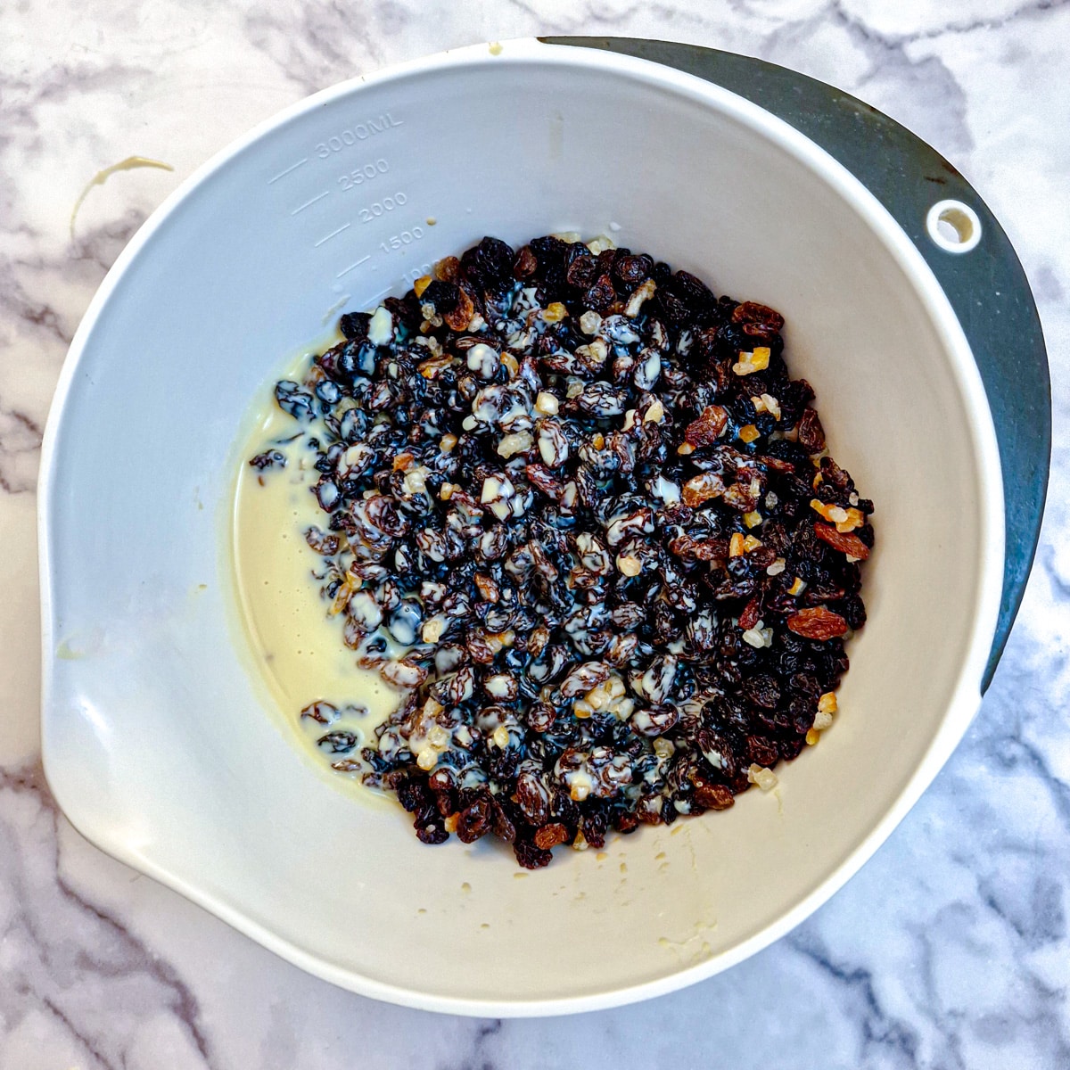 Mixed fruit in a mixing bowl with condensed milk.