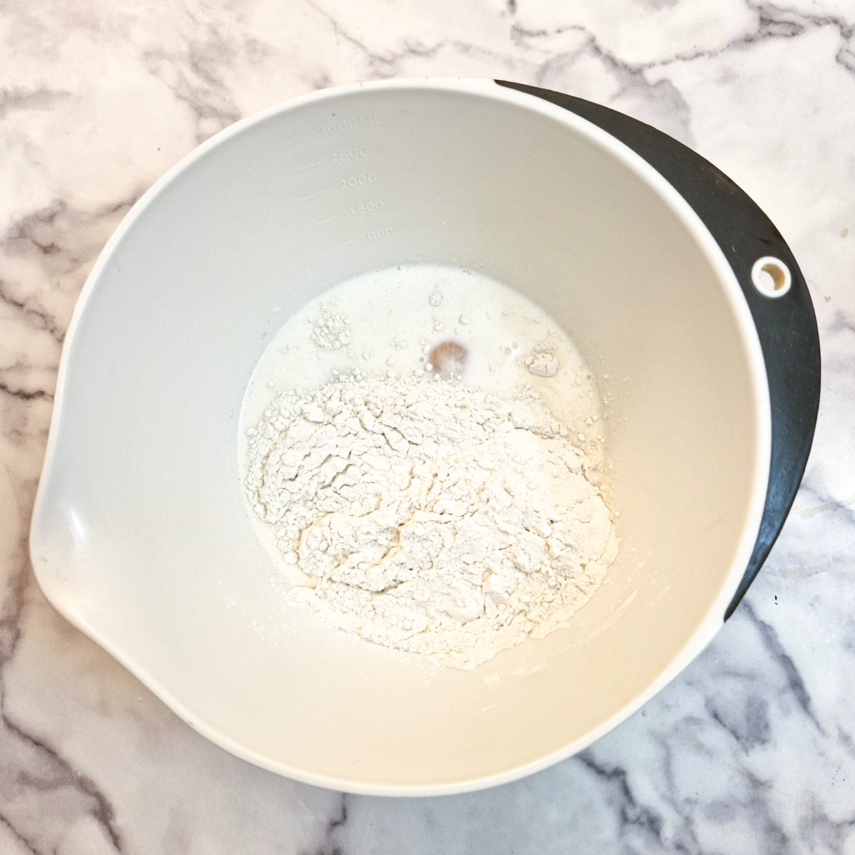 Eggs, flour, sugar and milk in a mixing bowl.