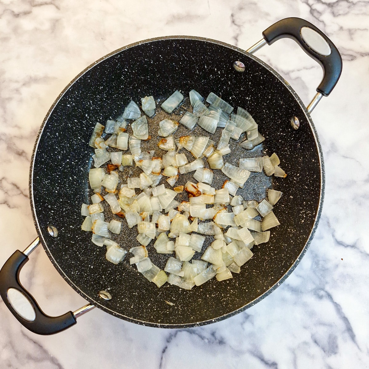 Chopped onions frying in a pan.