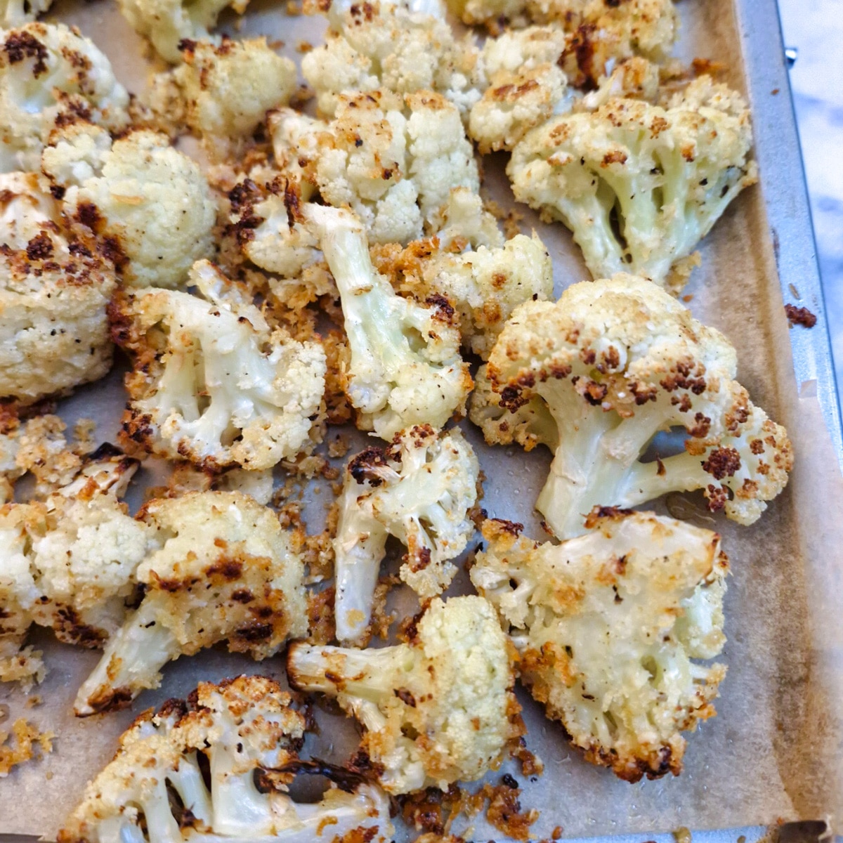 Fully cooked parmesan roasted cauliflower on a baking tray.