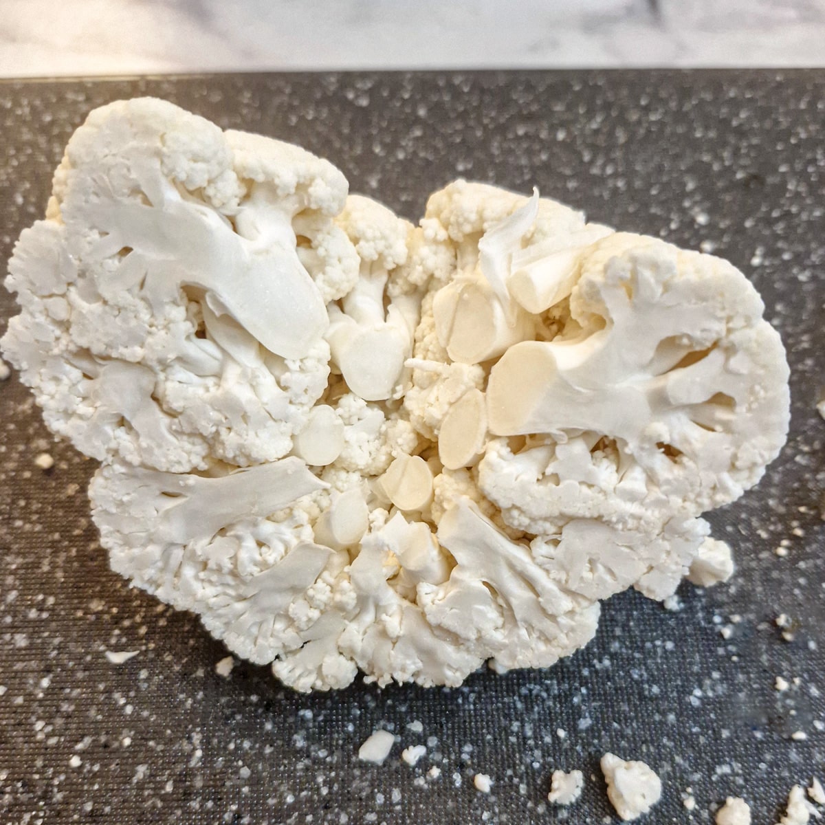 Close up of half a cauliflower with the core removed showing how the florets can be separated.