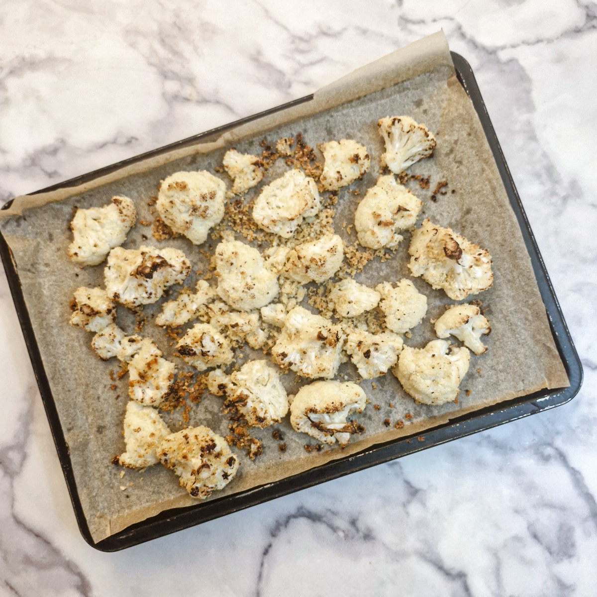 Parbaked cauliflower florets on a baking tray.