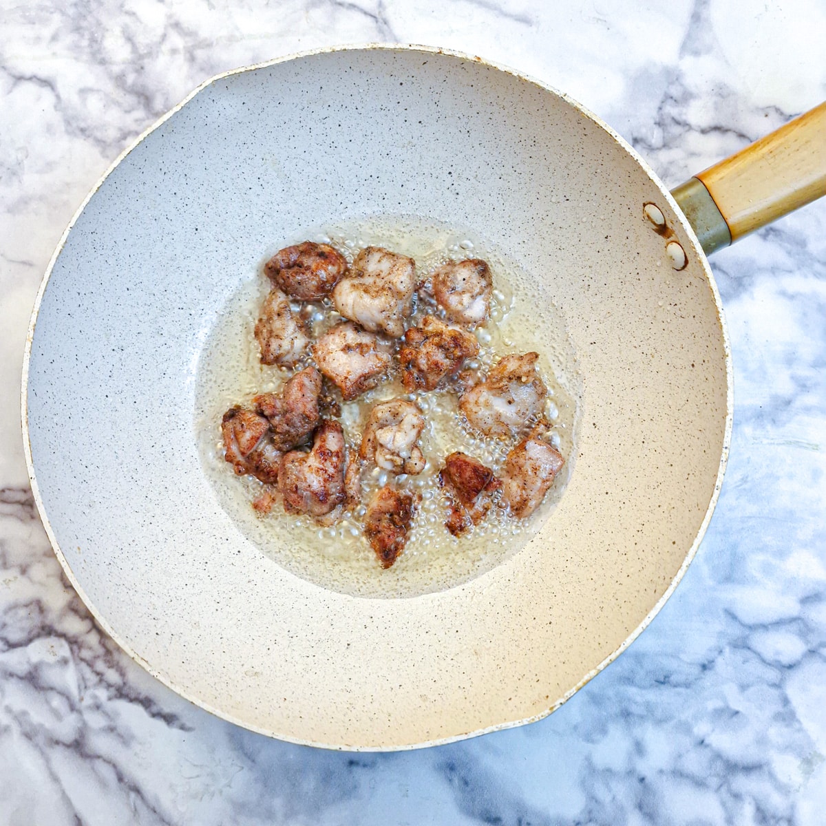 Browned crispy chicken pieces in a wok.