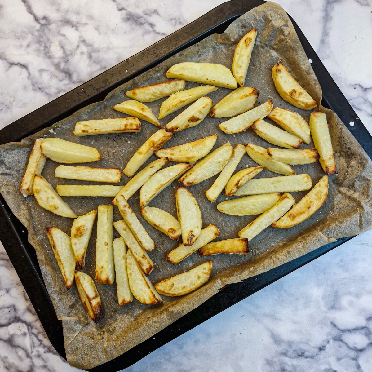 Cooked, browned chips on a baking tray.