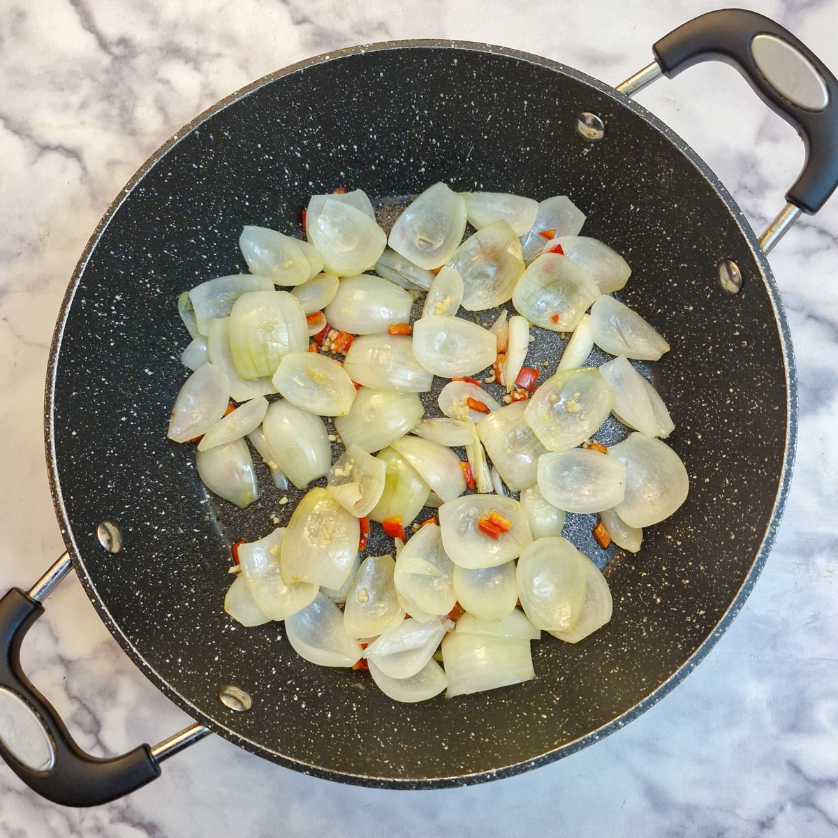 Translucent onions and chilli in a frying pan with garlic.