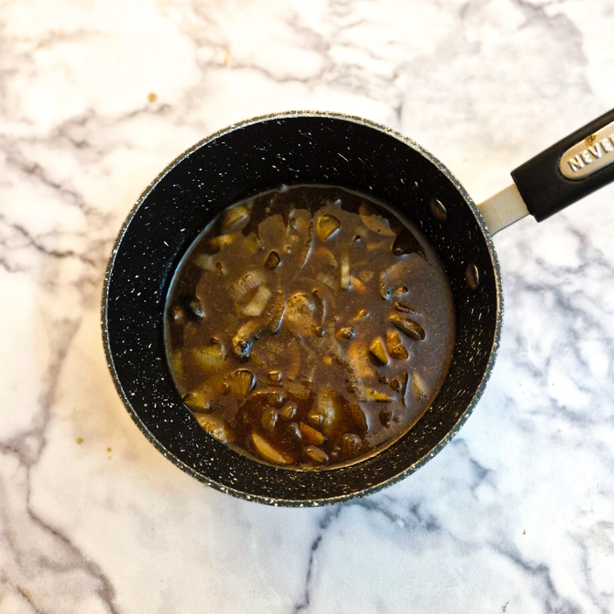 Stock, mushrooms and onions in a saucepan.