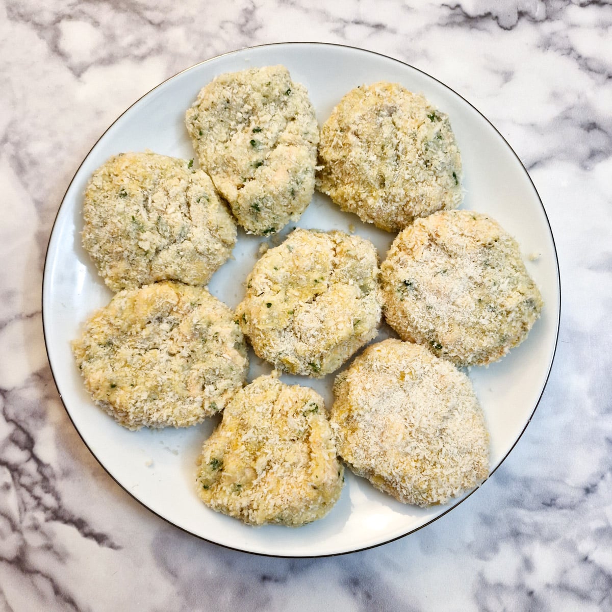 8 coated salmon fishcakes on a white plate.