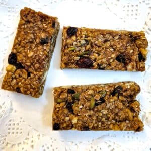 Three fruit and nut muesli bars on a white paper doily.