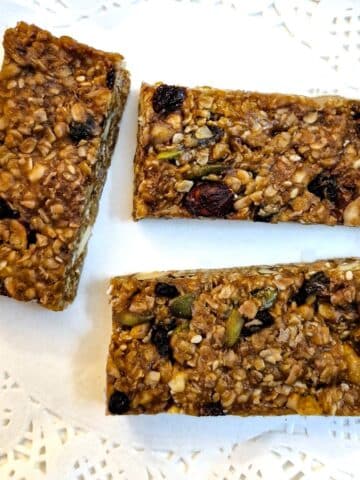 Three fruit and nut muesli bars on a white paper doily.