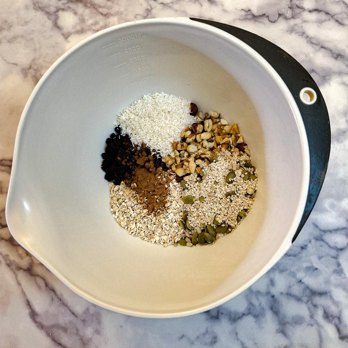 Dry ingredients for fruit and nut bars in a white mixing bowl.