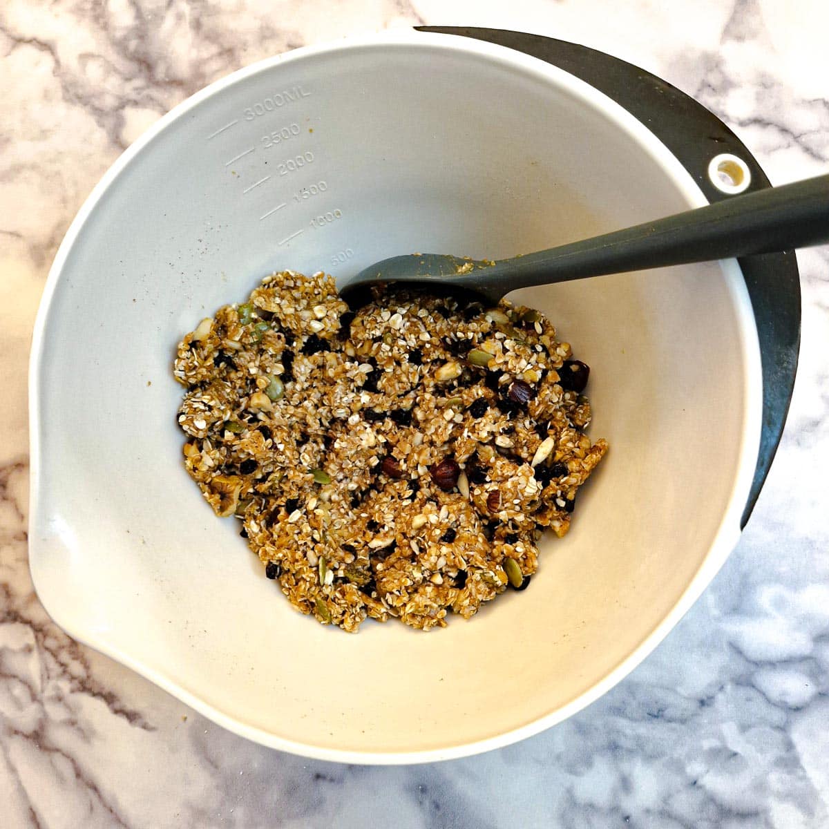 Penut butter and honey mixed with the dry ingredients in a white mixing bowl.