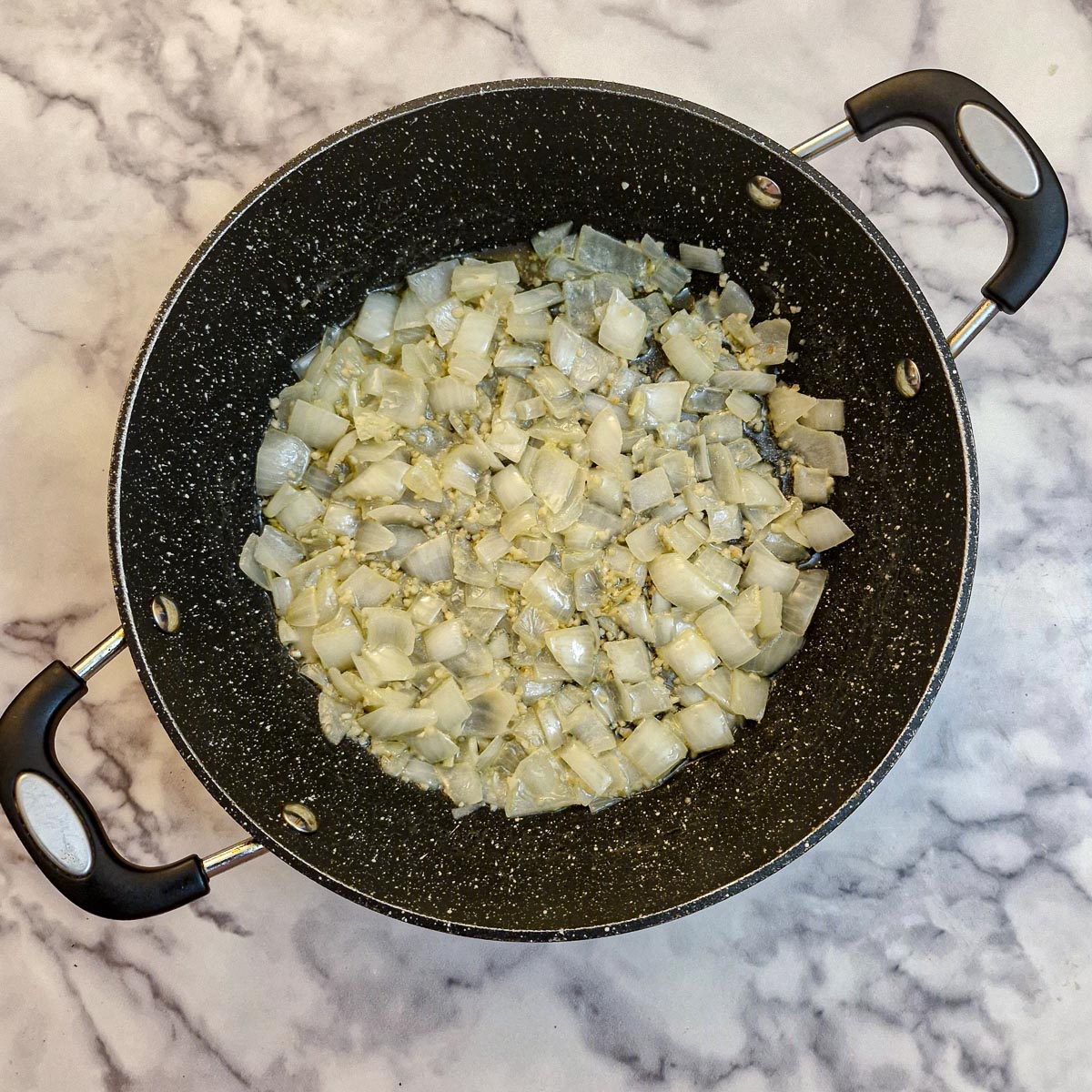 Onions frying in butter in a frying pan.