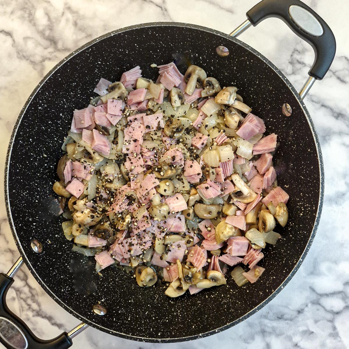 Ham and black peppercorns added to the frying pan.