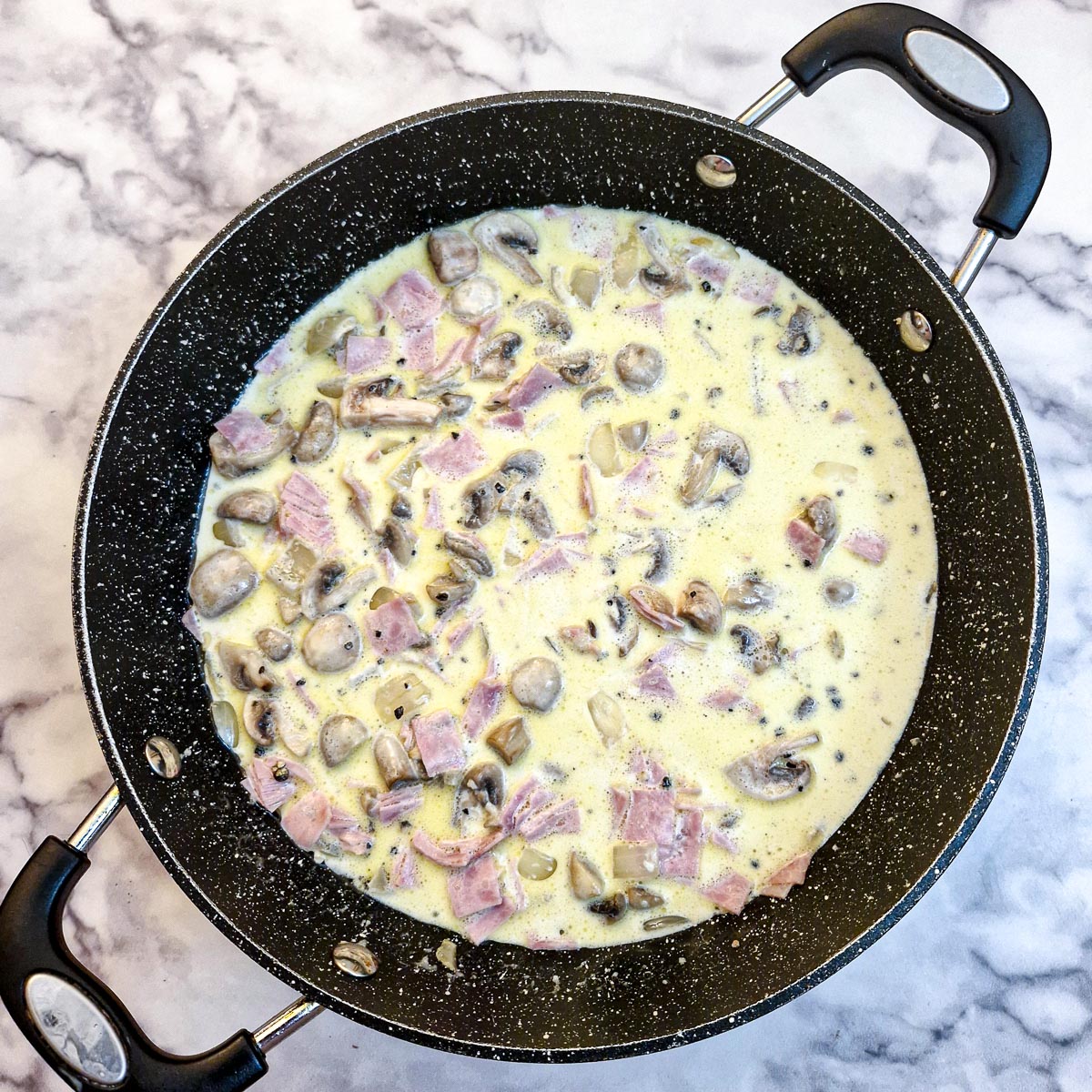 Unthickened milk and cream added to the pan with the other sauce ingredients.