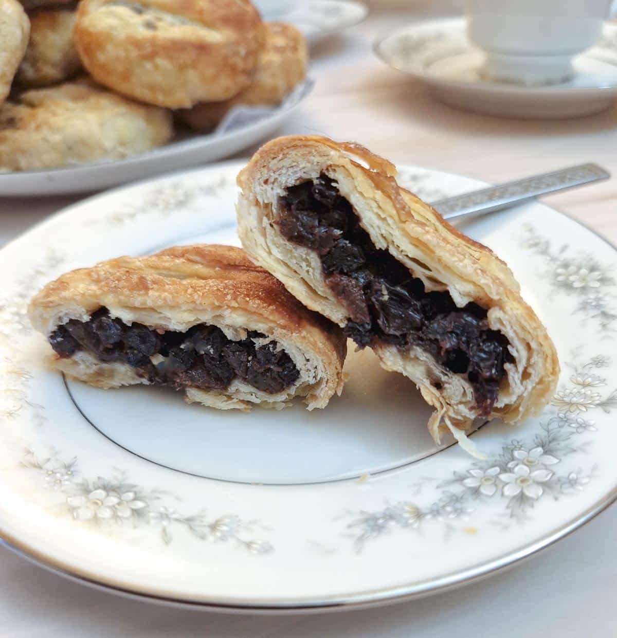 An eccles cake on a plate cut open to show the filling and the flakiness of the pastry.