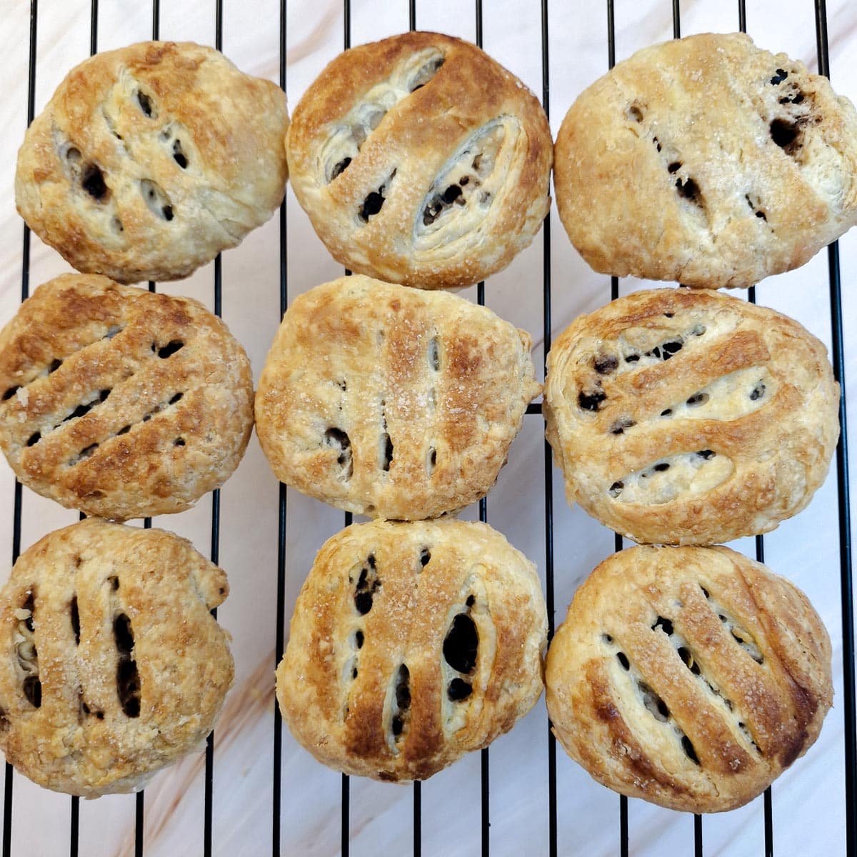 9 baked eccles cakes cooling on a wire rack.