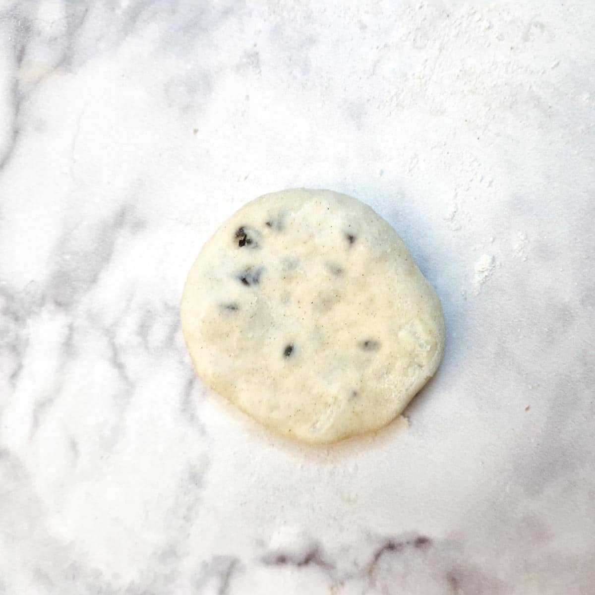 A completed raw eccles cake, pressed down slightly to flatten.