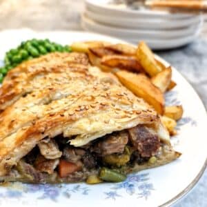 Leftover roast dinner pie on a plate, cut open to show the filling.