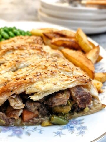 Leftover roast dinner pie on a plate, cut open to show the filling.