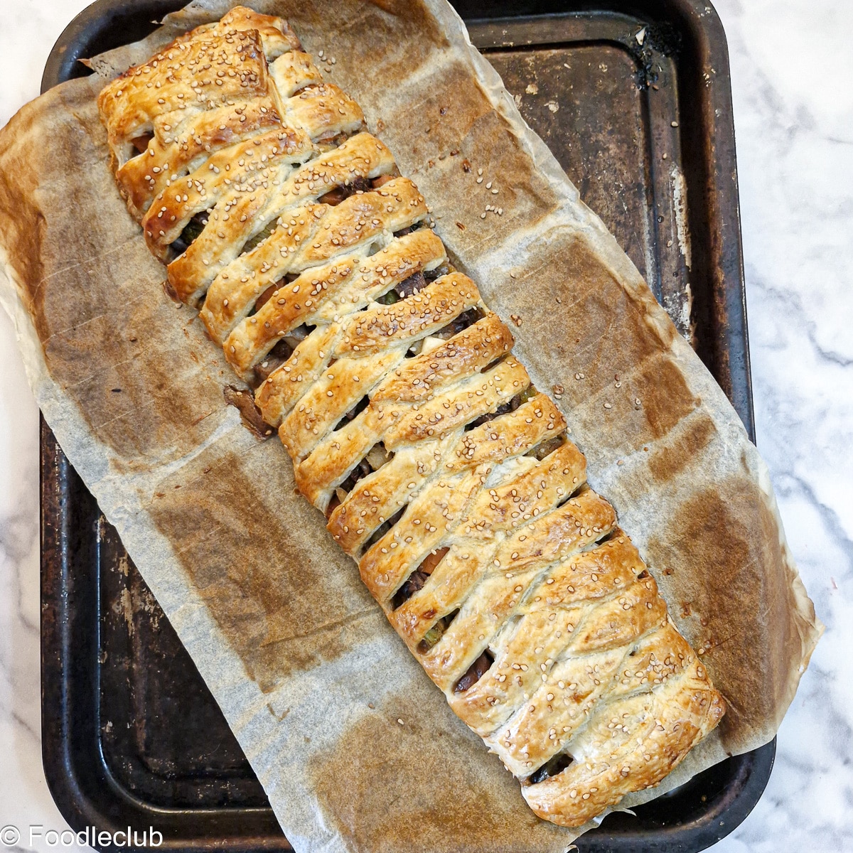 A full cooked leftover roast dinner pie on a baking sheet.