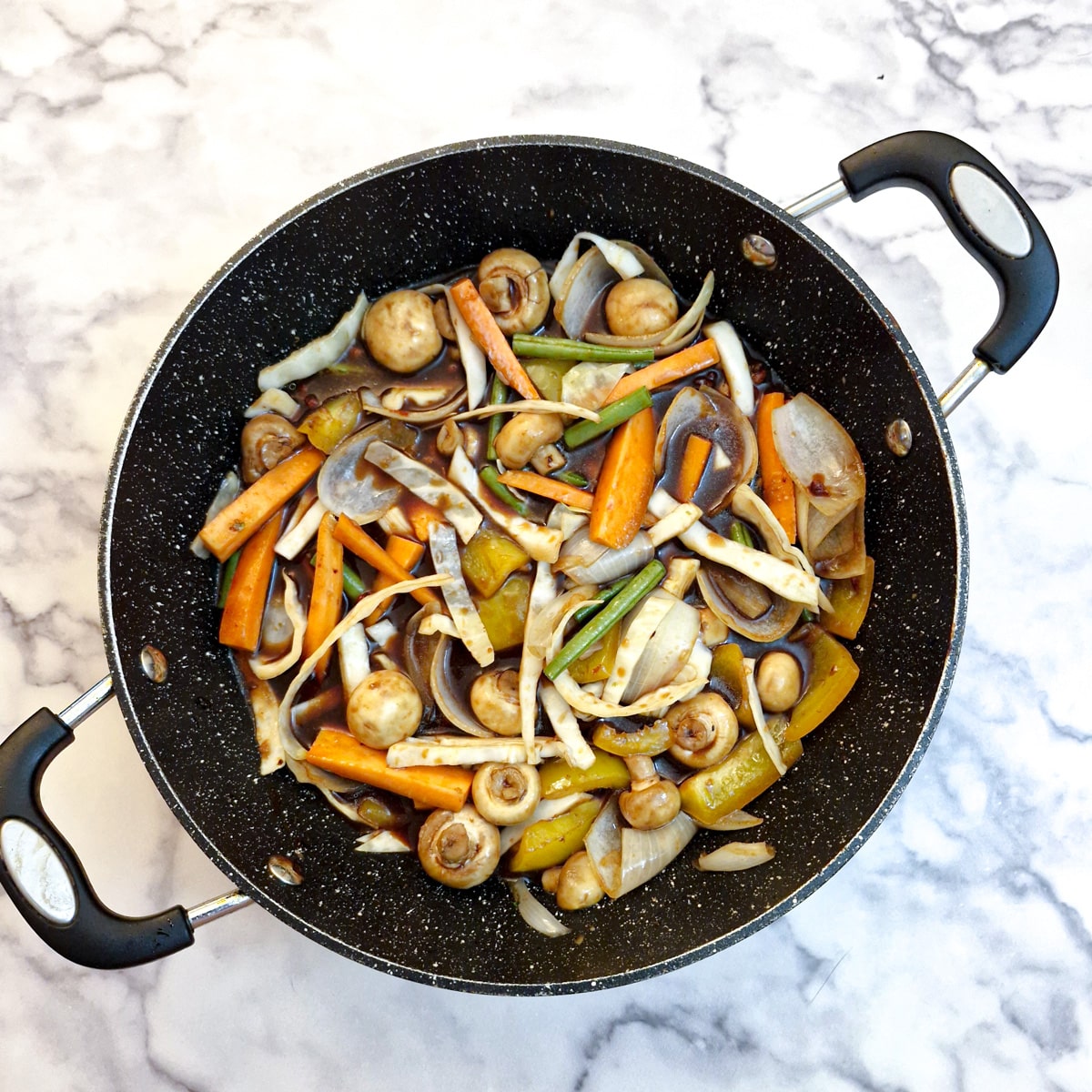 Softened vegetables for Szechuan chicken in a frying pan.