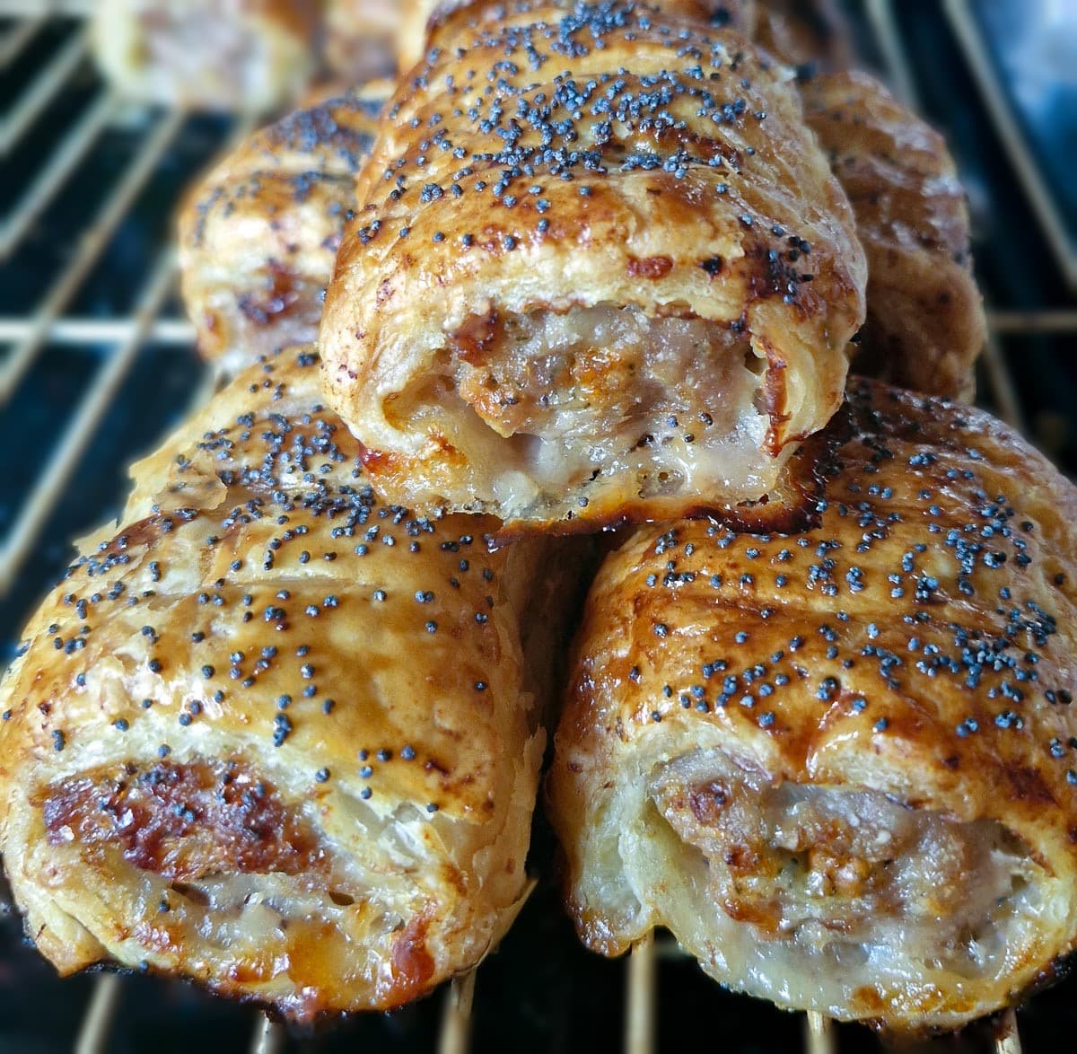 Closeup of 3 sausage rolls piled on top of each other.