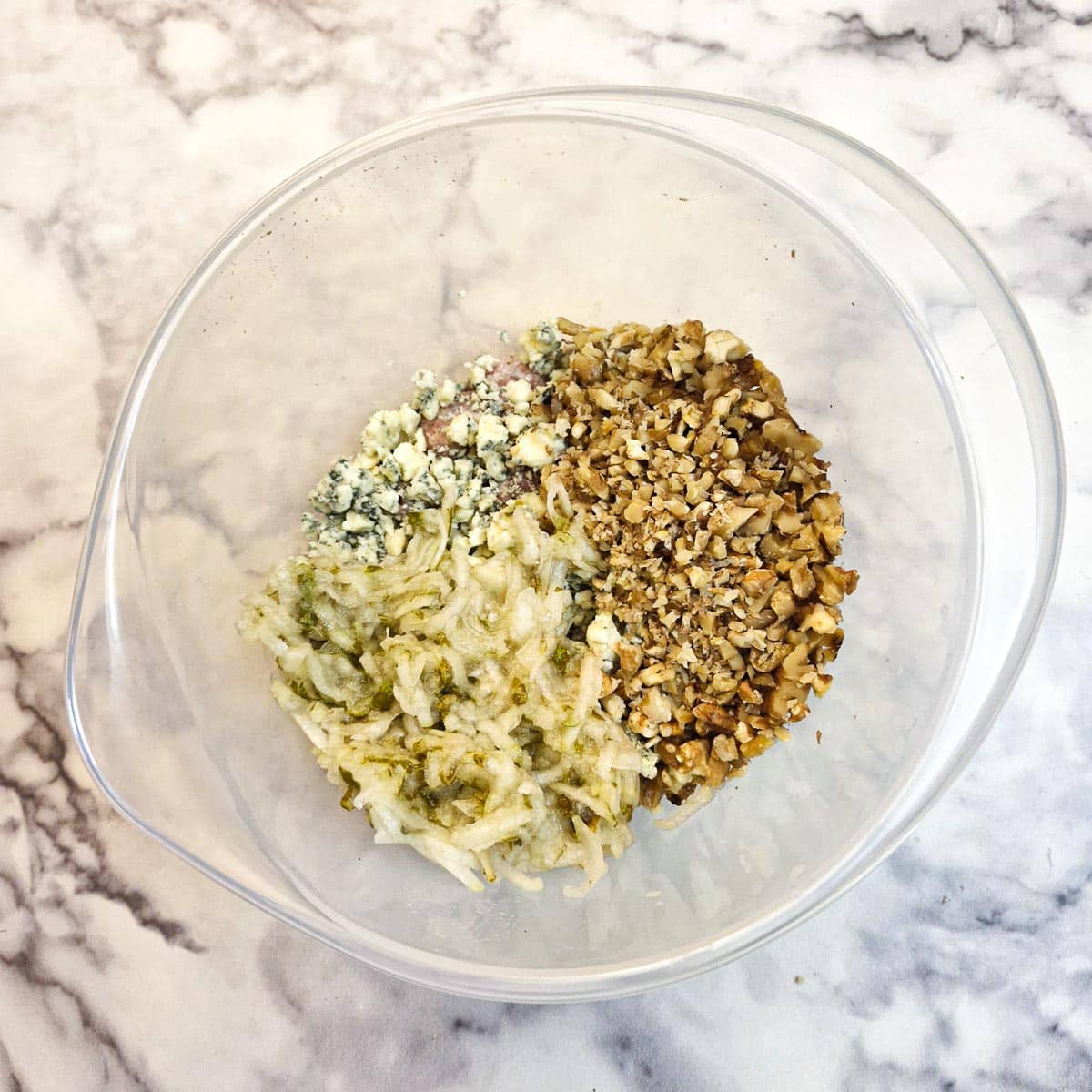 Chopped walnuts and grated pears added to the pork and cheese in a mixing bowl.