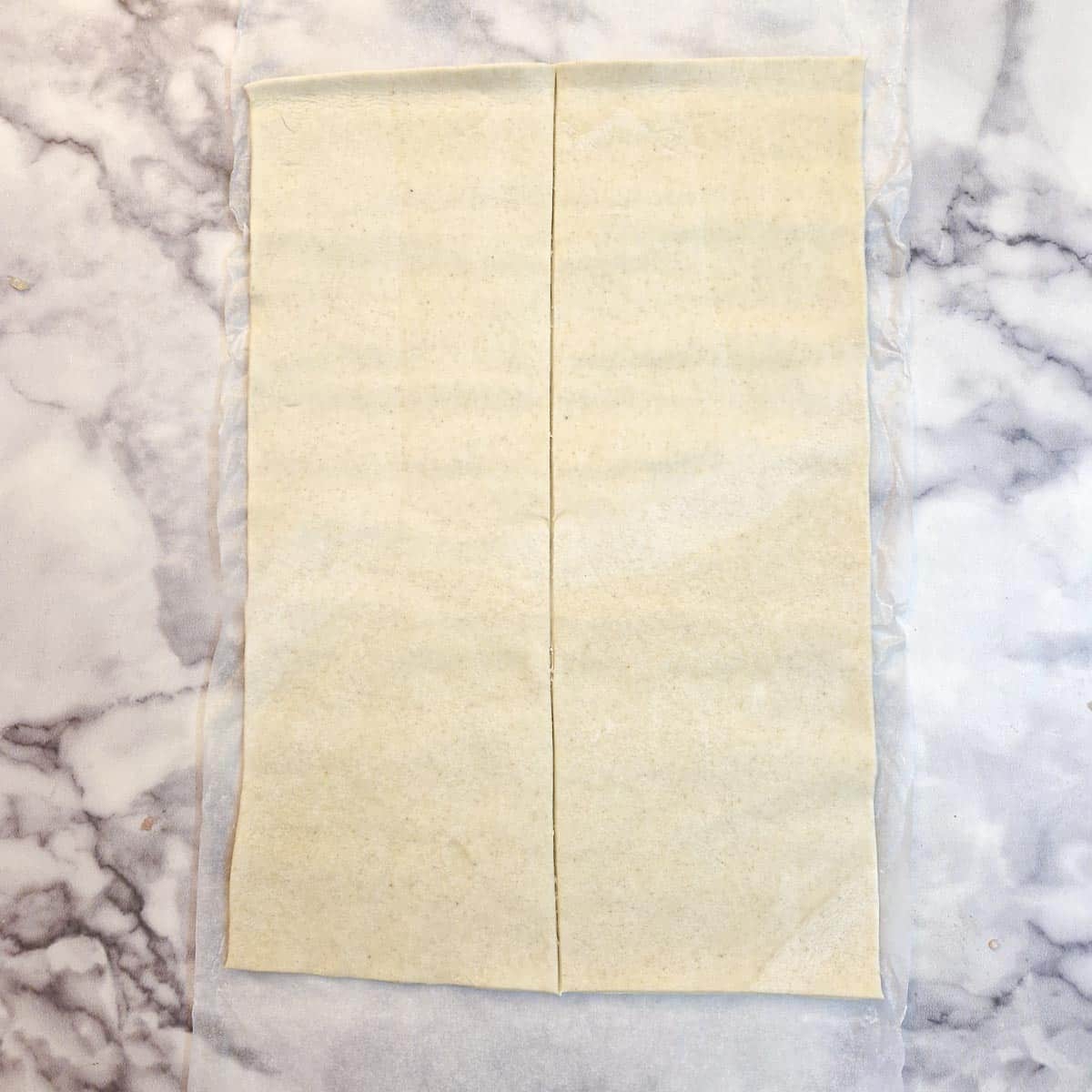 A sheet of unbaked puff pastry, unrolled and cut in half.