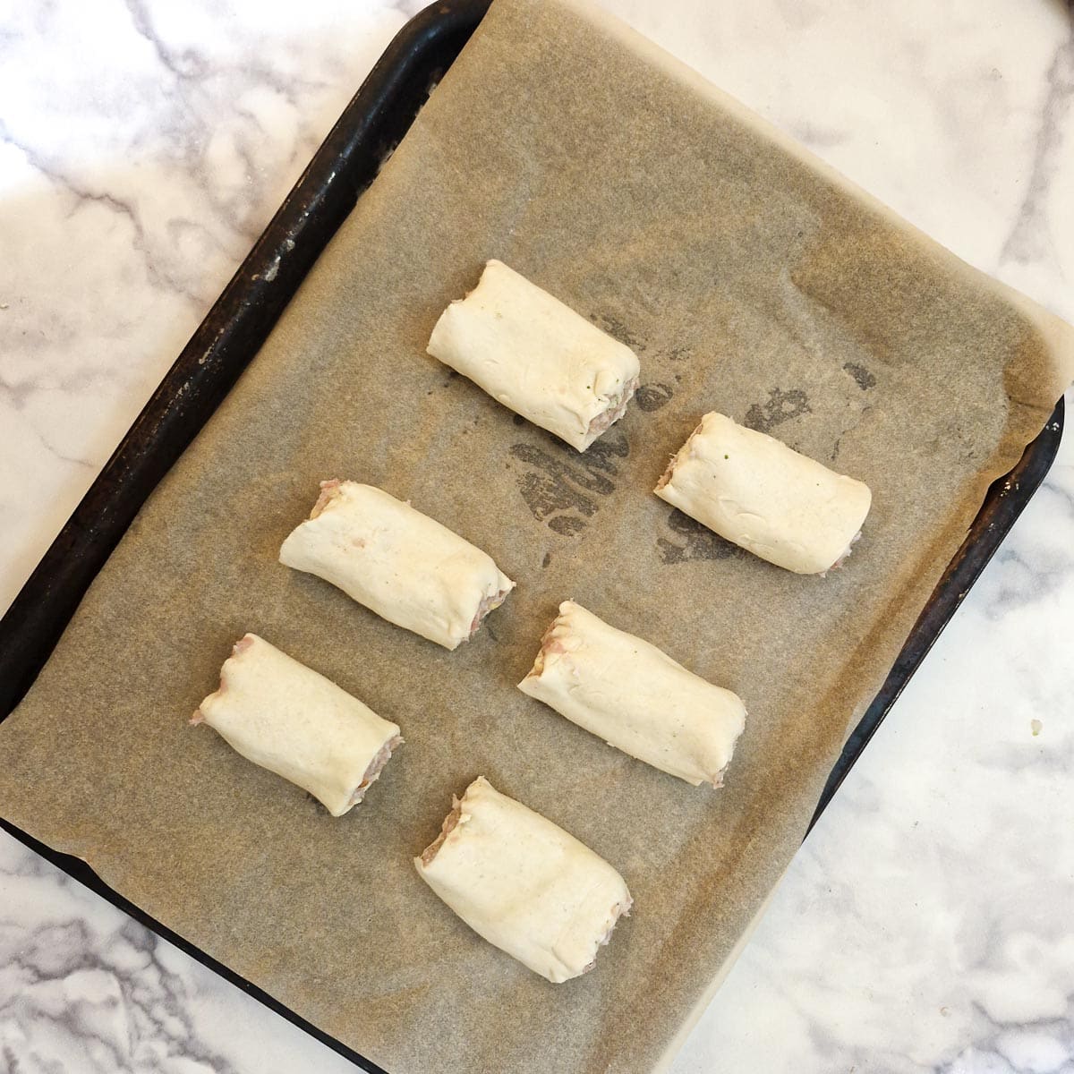 6 sausage rolls on a baking tray.