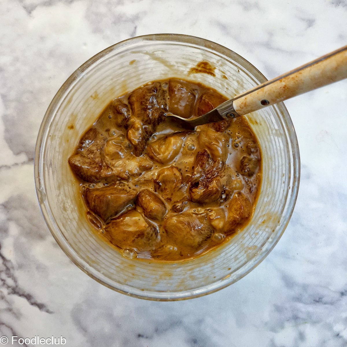 Chicken pieces mixed with egg and a soy/cornflour mixture in a glass bowl.