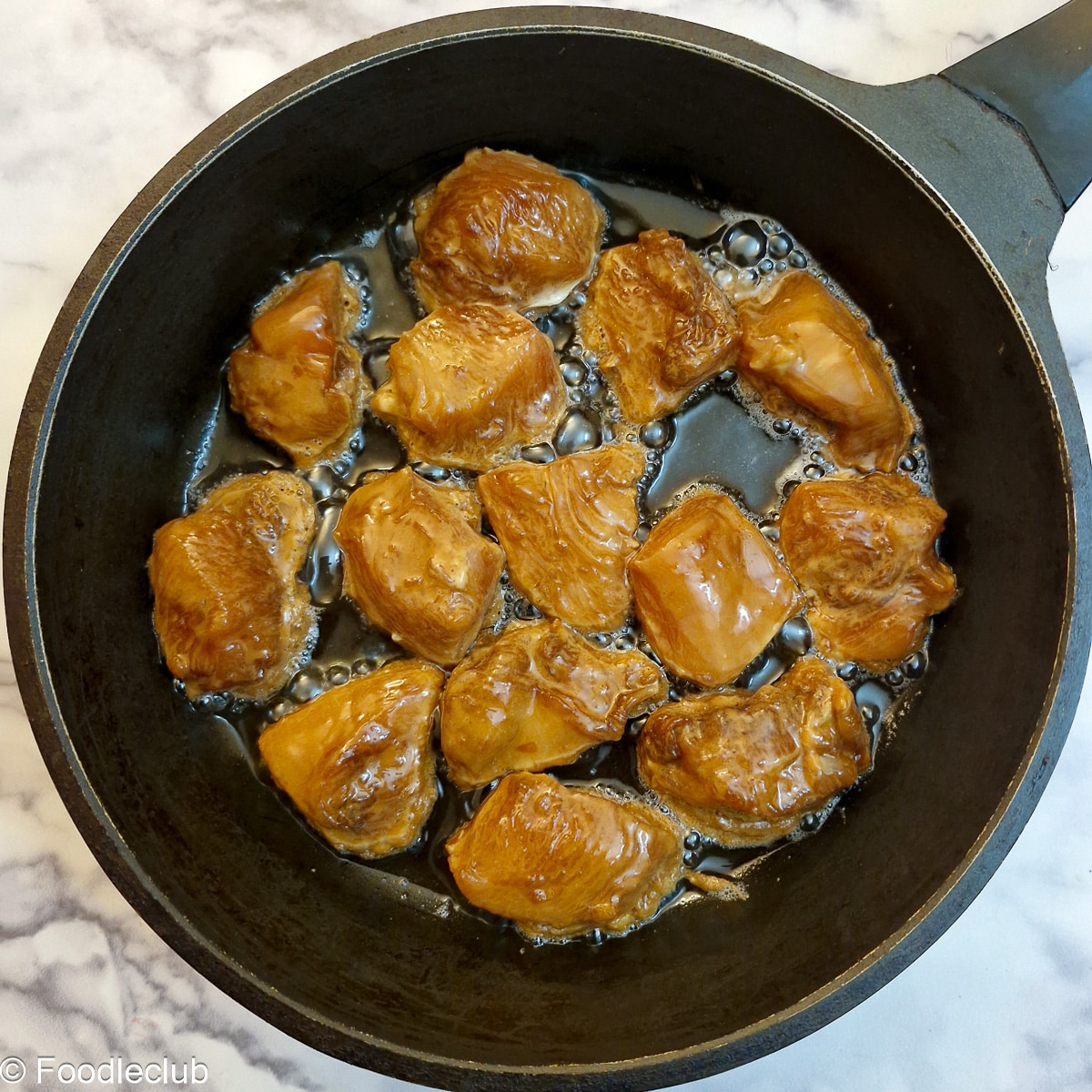 Chicken pieces browning in a frying pan.