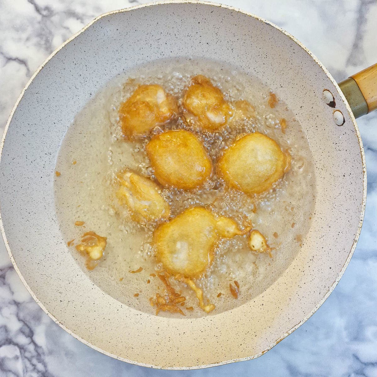 Chicken balls frying in oil in a wok.