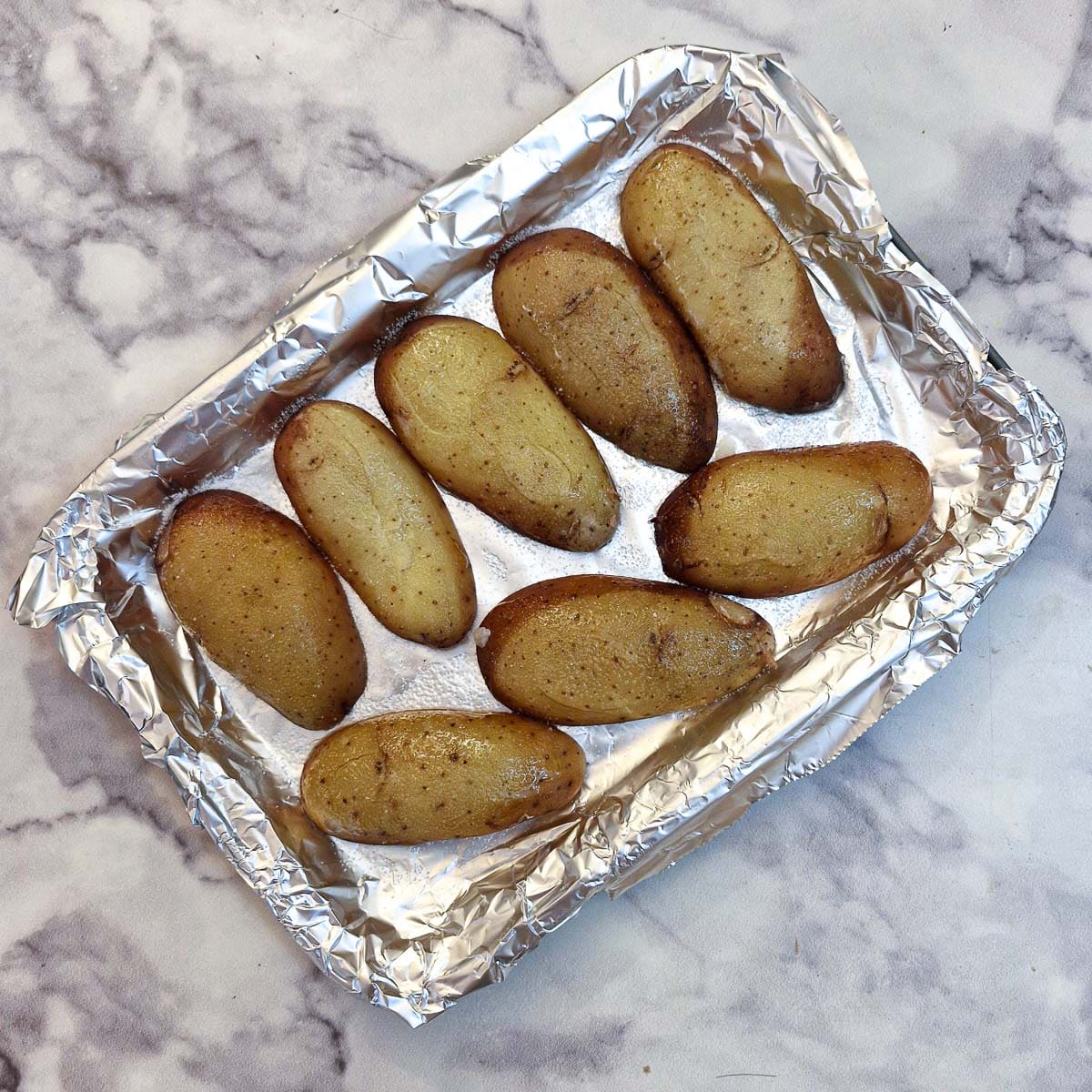 Baked potato skins arranged upside down on a baking tray.