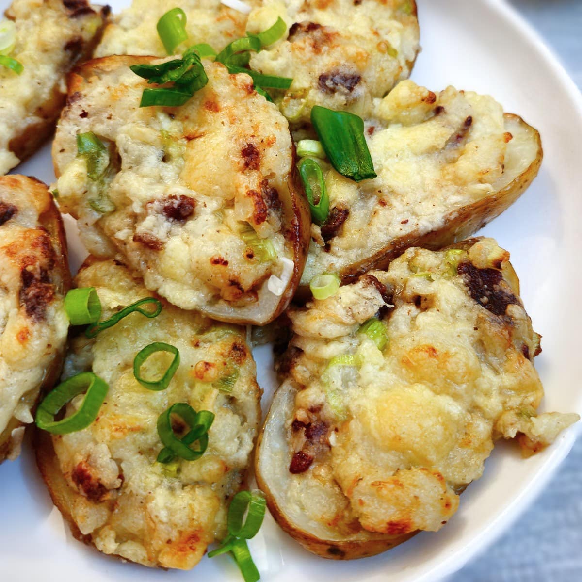 A white plate of cooked stuffed potato skins.