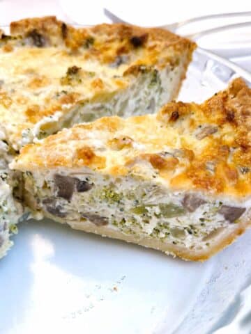 Side-on slices of cheese and broccoli quiche on a glass serving dish, showing the inside of the quiche.