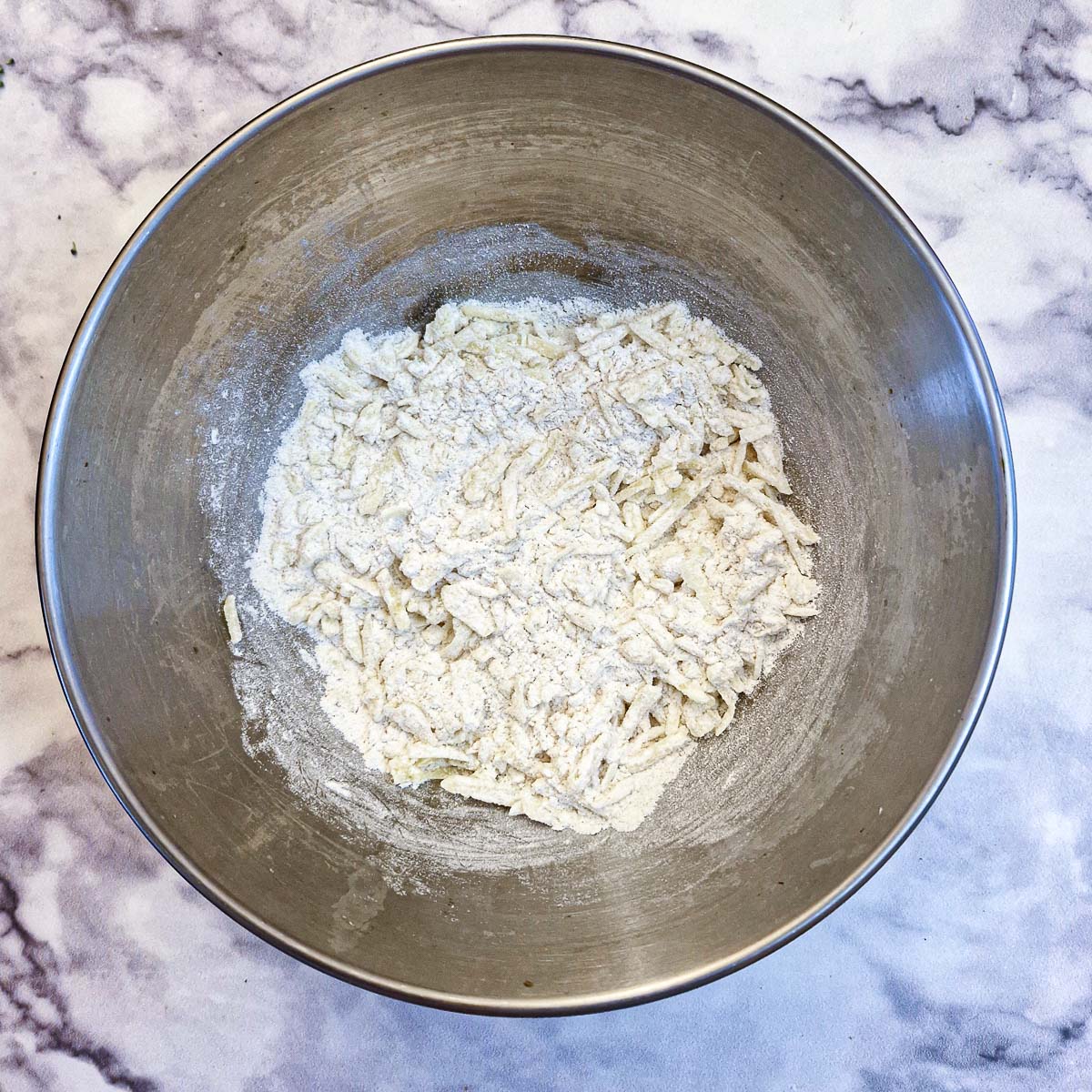 Flour and grated cheese combined in a mixing bowl.